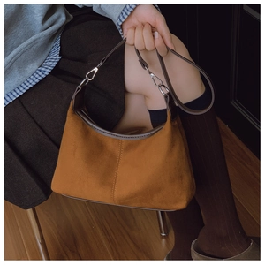 Detail view of brown suede underarm bag with leather trim and silver metal hardware