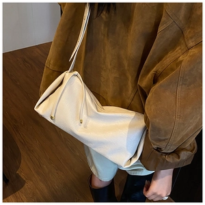 Détail du sac bandoulière blanc plissé avec boucles dorées sur une veste marron