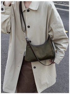 Detail of dark green suede crescent bag with brown leather trim and adjustable strap