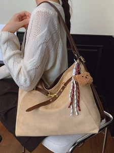 Beige suede tote bag with brown leather straps and cute bear charm worn by a model