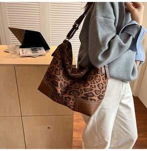 Detail of leopard print suede tote bag with brown leather trim and white stitching details