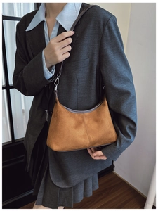 Detail view of large caramel vintage suede tote bag worn over a grey blazer jacket