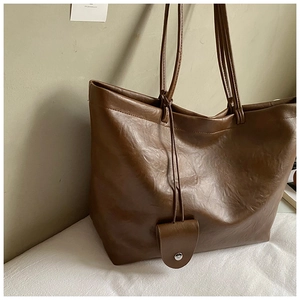 Λεπτομέρεια vintage σκούρας καφέ τσάντας tote από δέρμα PU με διακοσμητικό μεταλλικό μενταγιόν