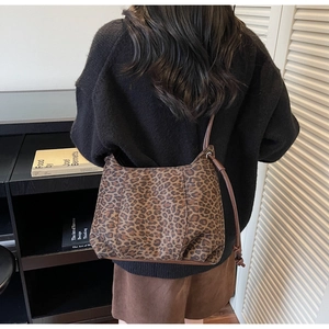 Detail of leopard print tote bag with brown leather straps worn over the shoulder