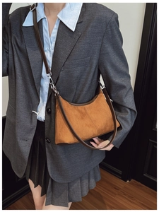 Close-up of brown suede hobo bag with deep brown leather trim on a grey blazer model
