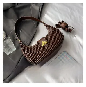 Detail showing woven texture on brown crescent bag with golden triangle clasp