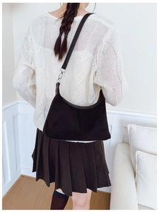 Rear view of model wearing black matte leather shoulder bag in a cozy home setting