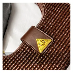 Detailed macro view of brown woven leather texture with a gold triangular metal buckle