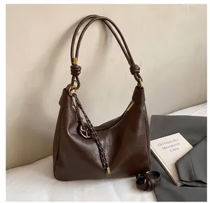 Detailed view of the dark brown leather hobo bag with knotted dual straps and metal pendant