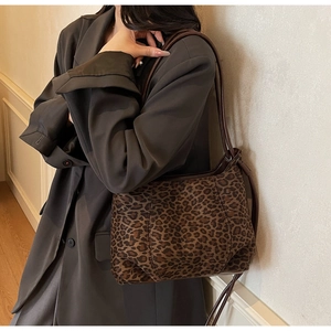 Leopard print tote bag with brown leather straps shown over a grey blazer for daily commute