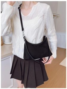 Detail of adjustable strap and silver buckles on a black crescent canvas shoulder bag