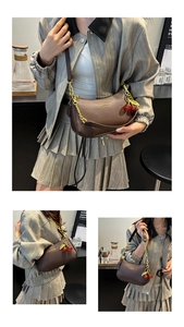 Détail du sac hobo en cuir grainé marron avec chaîne dorée et charm cerise