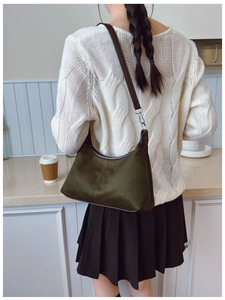 Detail of dark green retro shoulder bag with brown leather straps shown on a kitchen counter