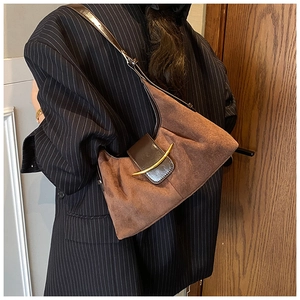 Détail du sac patchwork en daim avec boucle en corne dorée porté par un mannequin