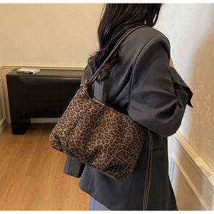 Detailed view of leopard print tote bag with brown leather straps on shoulder