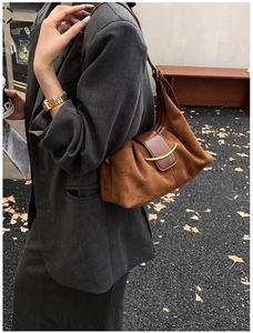 Détail du sac fourre-tout en daim avec boucle croissant dorée et finitions en cuir marron