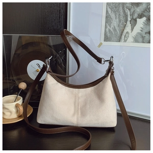 Close-up of beige suede hobo bag with brown leather trim in a cozy lifestyle setting