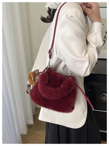 Detail of burgundy plush bucket bag with leather strap and leopard bow bear charm