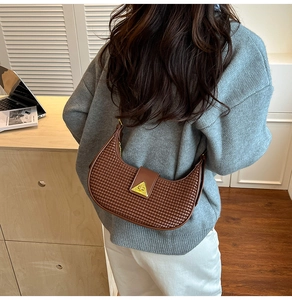 Close-up of brown woven leather hobo bag with a gold triangle buckle in a lifestyle setting