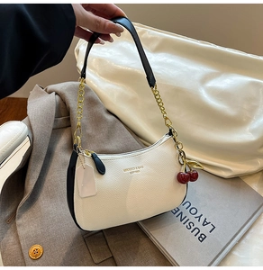 Détail du sac en cuir grainé blanc avec breloque cerise et chaîne dorée