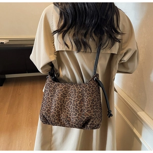 Detailed back view of a leopard print tote bag with stylish knot strap on a beige trench coat