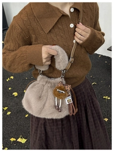 Detail of plush bucket bag with faux fur texture, doll charm and leather strap