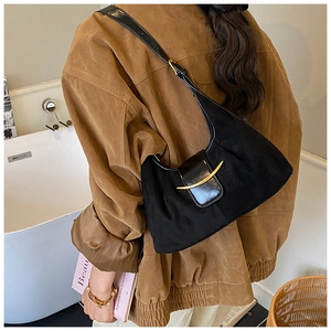 Détail du sac sous l'aisselle en daim noir avec boucle dorée et bandoulière
