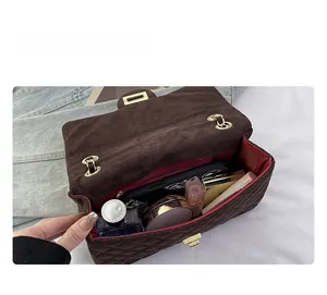 Detailed internal view of brown velvet quilted crossbody bag showing spacious red interior