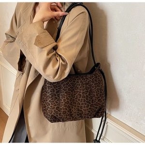 Detail of vintage leopard print tote bag with black leather strap on beige trench coat
