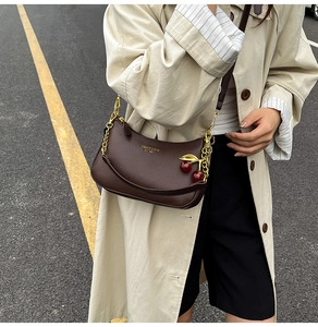 Détail du sac bandoulière en cuir grainé chocolat avec pendentif cerise et bandoulière