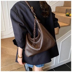 Close-up of a large dark brown Hobo bag with a unique knotted strap on a model's shoulder