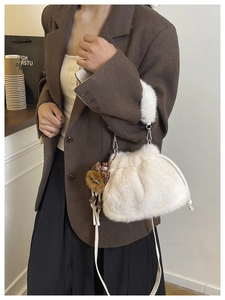 Close-up of white plush bucket bag with leopard print bow charm and slim leather strap