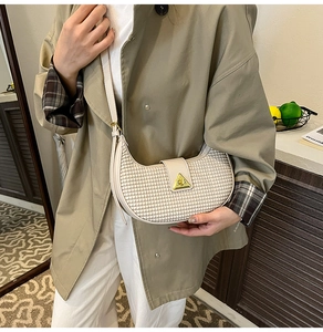 Detail of off-white crescent bag with woven texture and gold triangular buckle