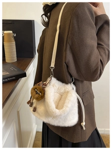 Detail of white plush faux fur bucket bag with a cute leopard-pattern doll charm