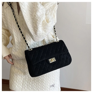 Detail of black quilted velvet crossbody bag featuring a pale gold chain strap and turn-lock