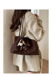 Detail view of brown suede tote bag with decorative baseball and dachshund dog charms