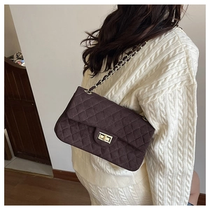 Detail of dark brown quilted crossbody bag with golden twist lock and chain strap