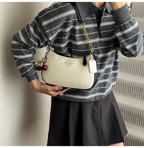 Détail du sac hobo blanc cassé avec pendentif cerise et bandoulière en chaîne