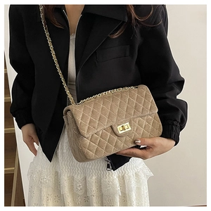Detail of beige quilted shoulder bag with gold chain strap and metal turn-lock closure