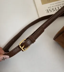 Detalle de la correa larga ajustable con hebilla dorada en un bolso tote marrón
