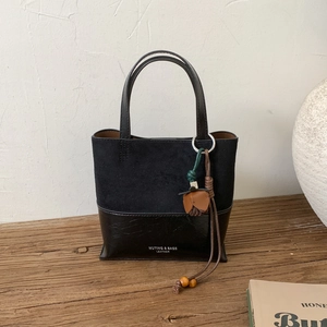 Detail of dual-texture black leather tote bag with matte finish and brand logo