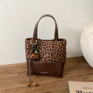 Detail of leopard print stitching and leather bucket bag with decorative floral tassel
