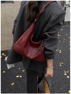 Detail of wine red leather hobo bag featuring knotted shoulder strap and metal buckle