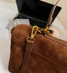 Detalle de hebilla metálica dorada en bolso tote de ante marrón con costuras finas