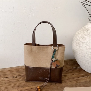 Close-up of leopard print stitching and wooden bead charm on a leather bucket bag