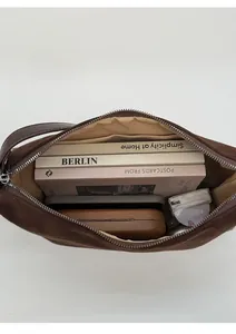 Deep brown suede crossbody bag showing spacious interior with books and phone