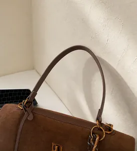 Detalle del asa del bolso tote de ante marrón con elegante cierre de anillo dorado