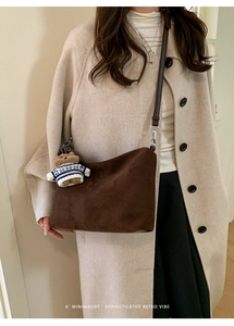 Detail of dark brown suede tote bag featuring a cute plush bear pendant and silver buckle