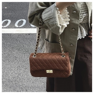 Macro detail of brown quilted suede leather bag with gold twist lock and chain strap
