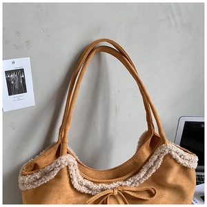 Detail of suede tote bag featuring fuzzy shearling trim and decorative bow tie accent